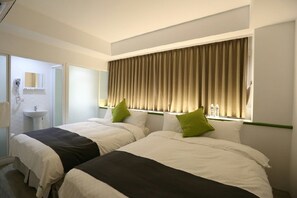 Une chambre d’hôtel avec deux lits, une fenêtre avec des rideaux, un lavabo et un miroir.
