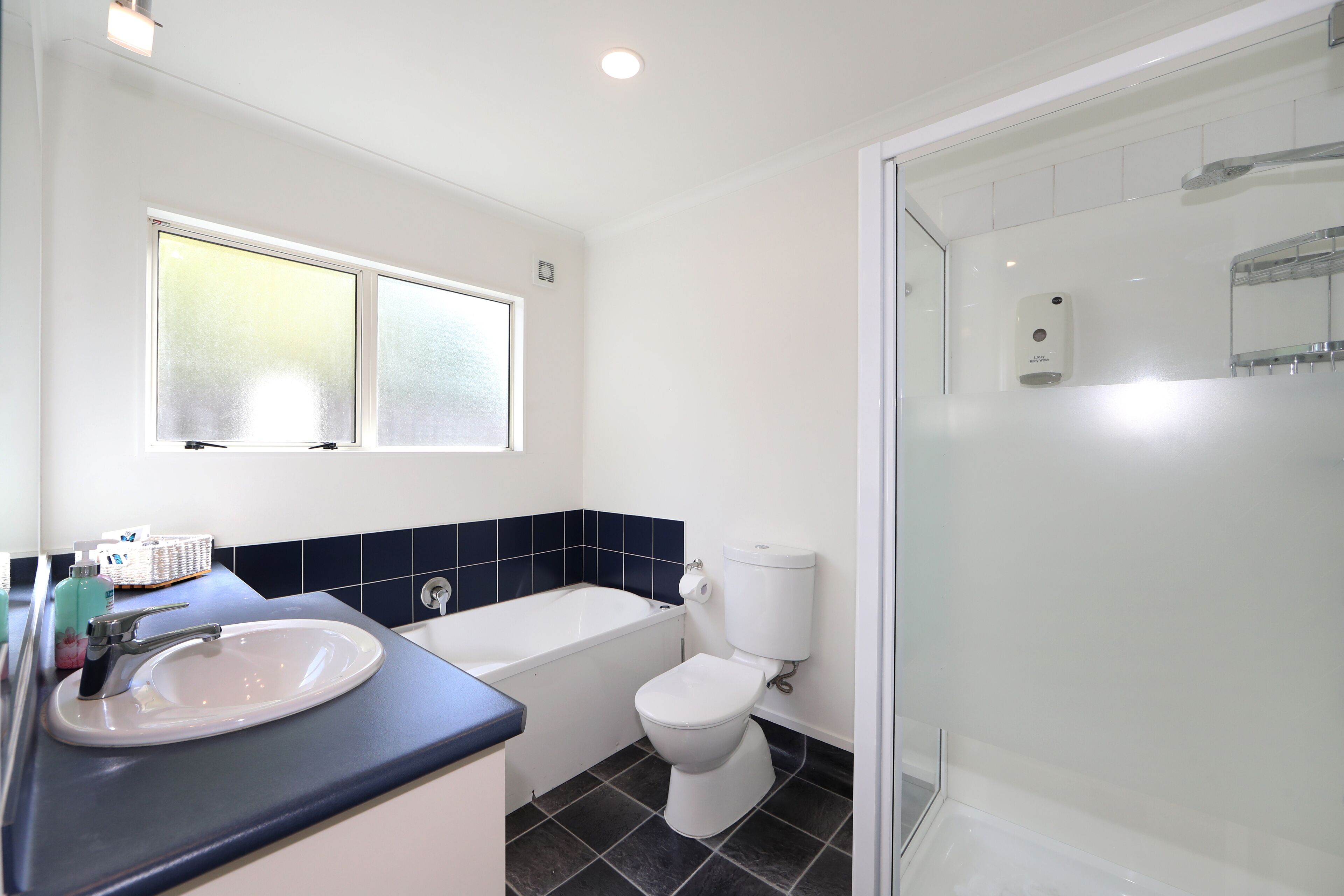 A modern bathroom with a white sink, bathtub, and toilet.