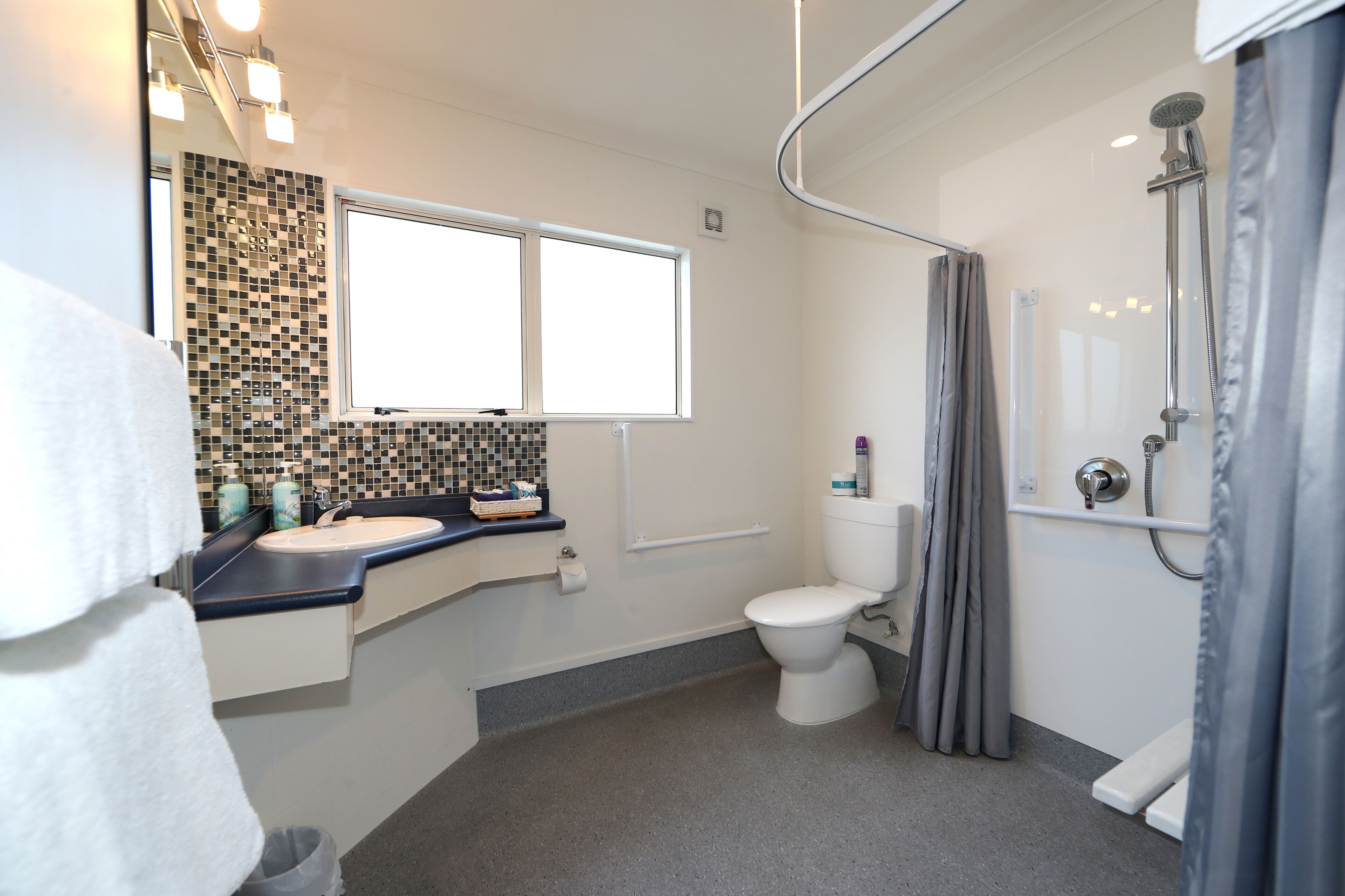 Un baño moderno con inodoro, lavamanos y ducha.