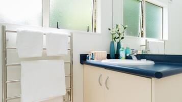 A bathroom with a towel rack, a sink, and a window with frosted glass.