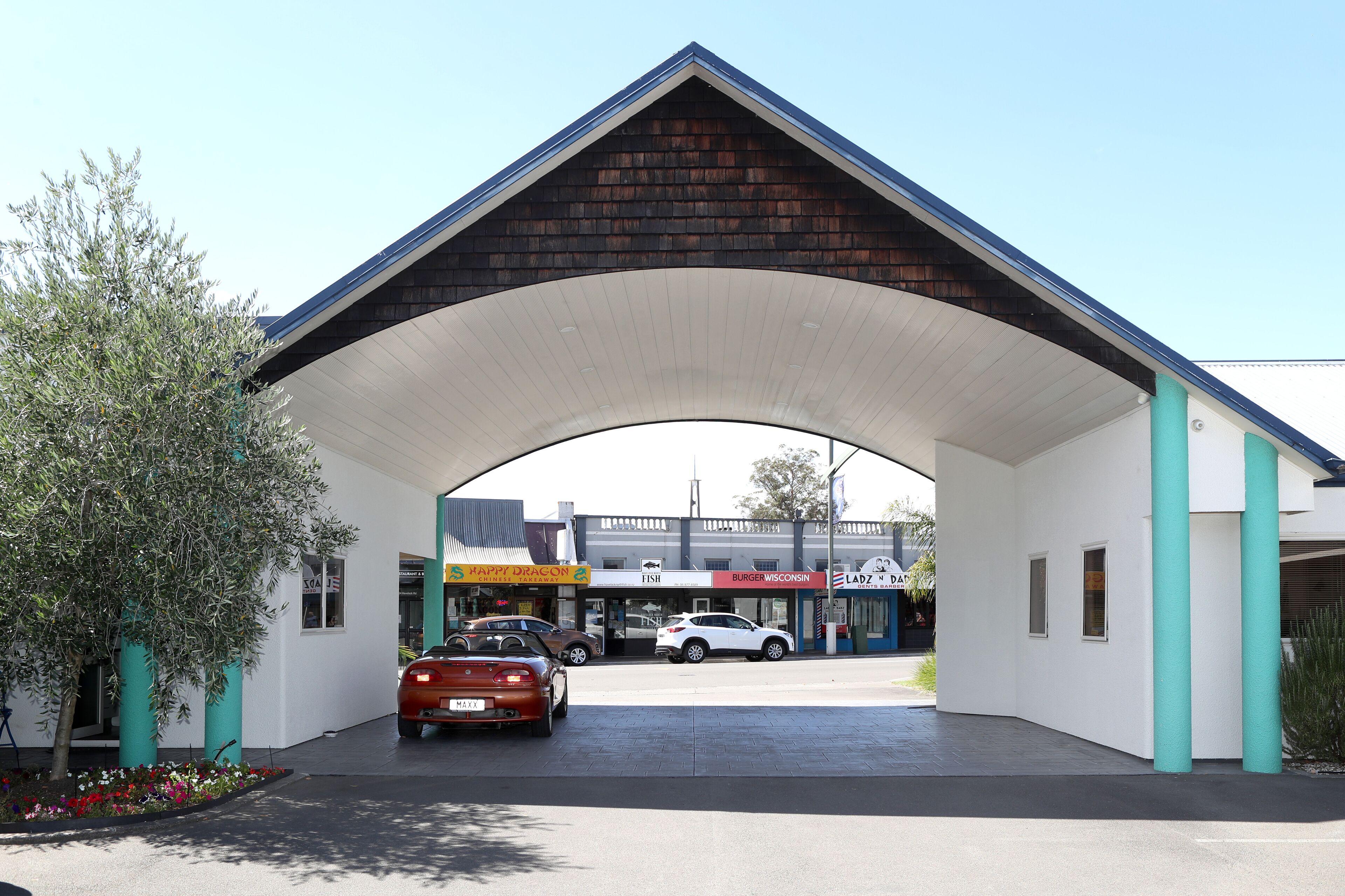 Ett överbyggt parkeringsområde med ett tak av tegel och vita väggar, som leder fram till en byggnad med en skylt som visar texten ”Burger Wisconsin”.