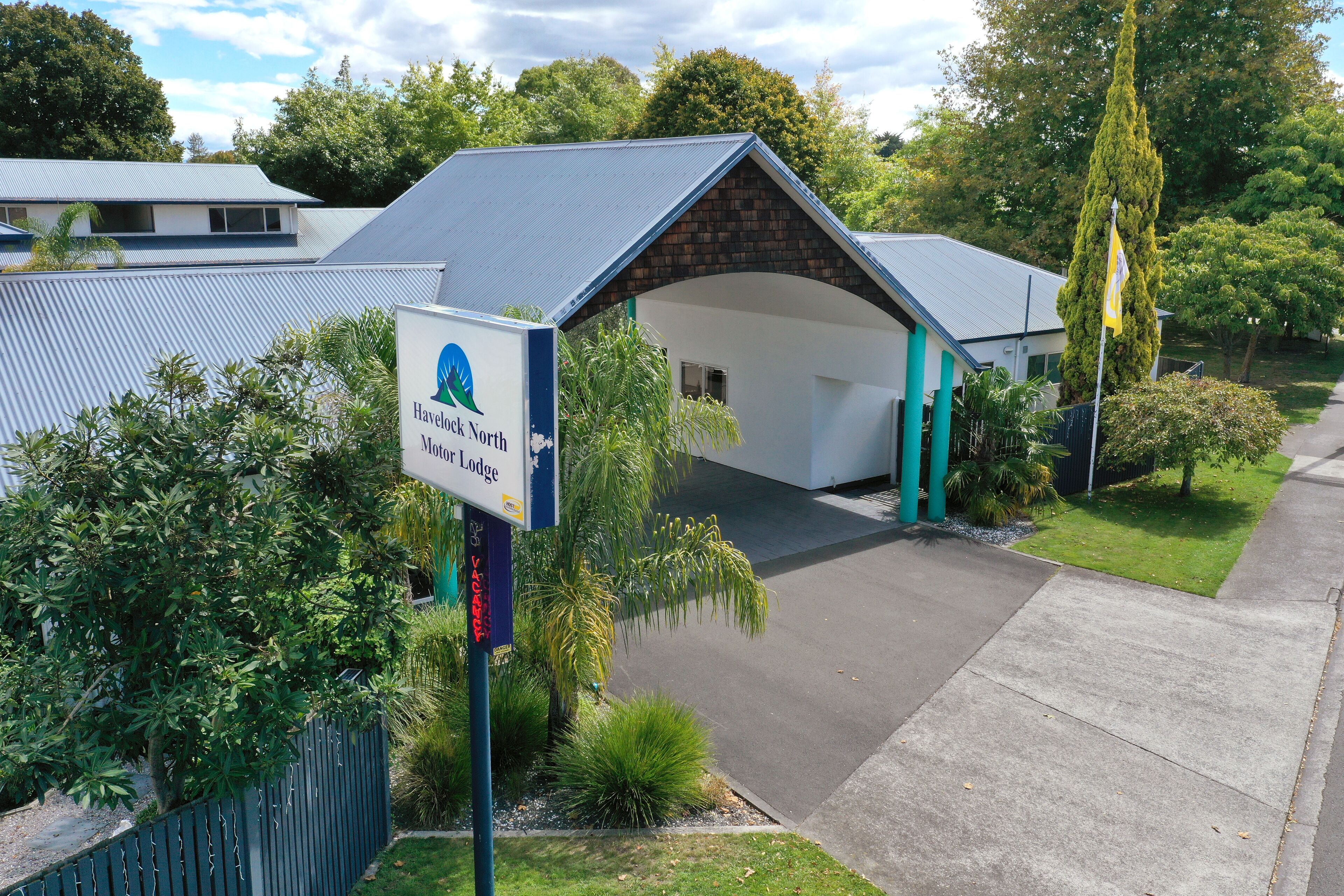 A lodge with a covered entrance, surrounded by greenery and a clear sky.