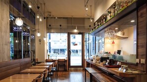 Ein Restaurantinneres mit Holztischen und -stühlen, einer Theke mit Registrierkasse und Blick durch die Tür.