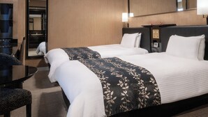 Ein Hotelzimmer mit zwei Betten, einem Schreibtisch, einem Stuhl und einem großen Spiegel.