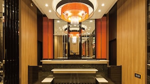 Eine moderne Lobby mit einem zentralen Kronleuchter, Marmorböden und Holzvertäfelung.