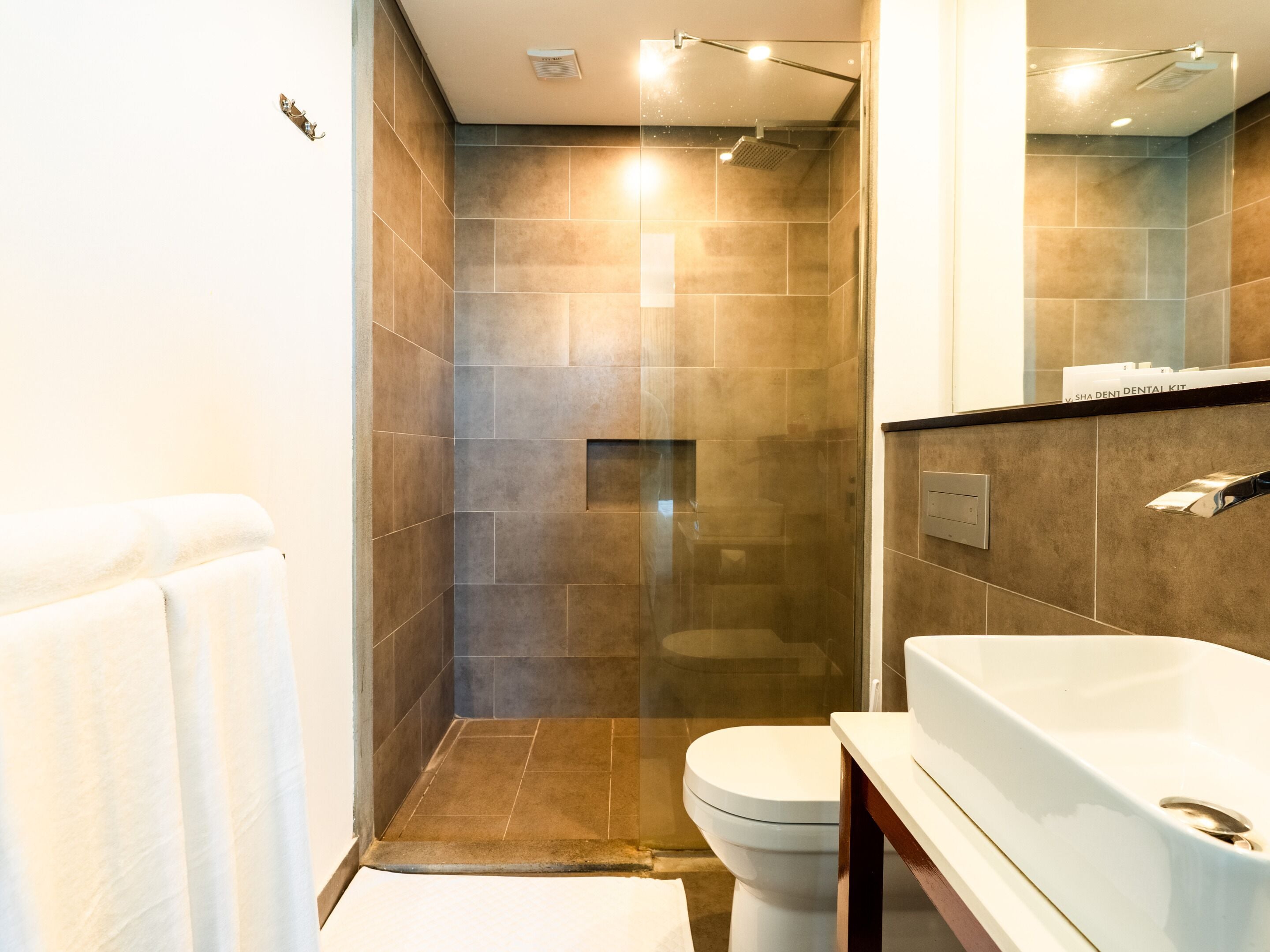 Un baño moderno con ducha a ras de suelo, inodoro y bañera.