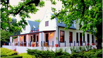 Experience the charm of a traditional building with a symmetrical design and a welcoming entrance, surrounded by lush greenery.