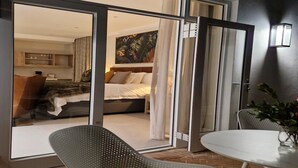 Ein modernes Hotelzimmer mit Bett, Sitzgelegenheit und Blick durch eine Glastür.