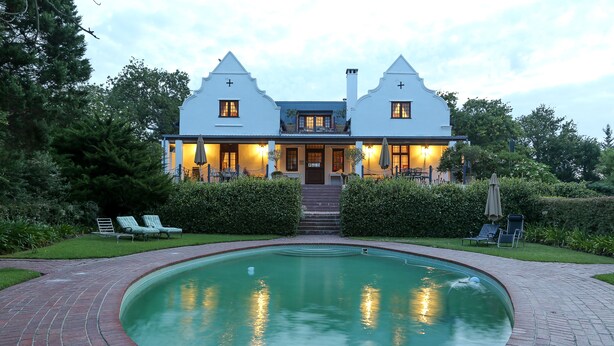 Ein zweistöckiges Haus mit einem Pool davor.
