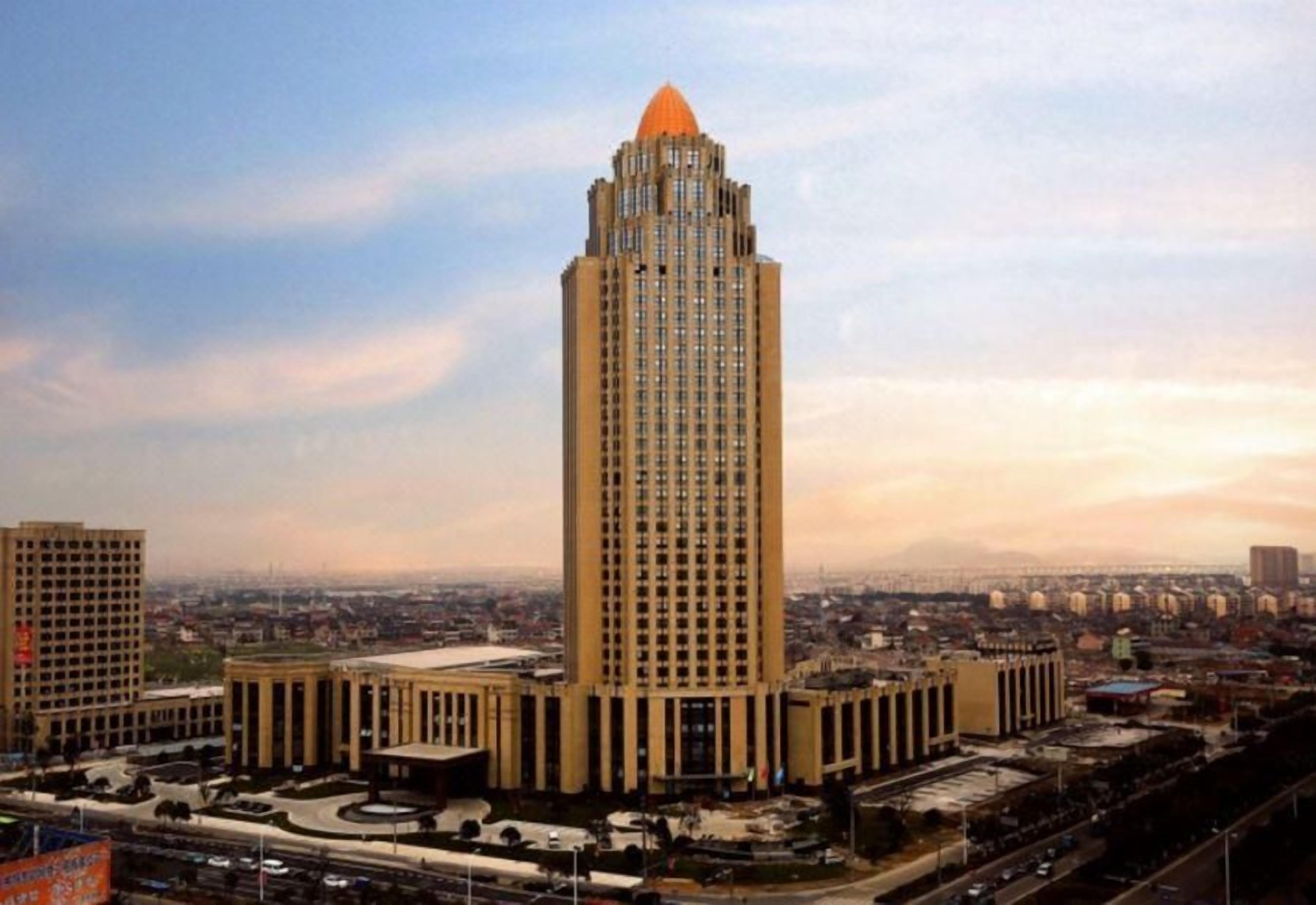 Un edificio de gran altura con una parte superior distintiva, rodeado de un paisaje urbano.
