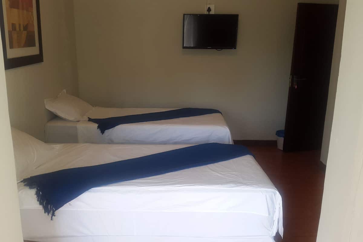 Una habitación con dos camas, un televisor en la pared y una puerta.