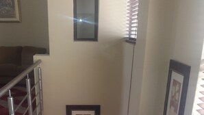 A staircase with metal railings, a framed picture on the wall, and a window with blinds.