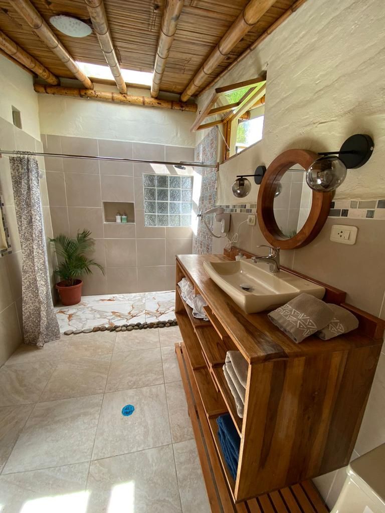 Ein Badezimmer mit einem Holzbadezimmerhocker, einer Duschkabine und gefliestem Boden.