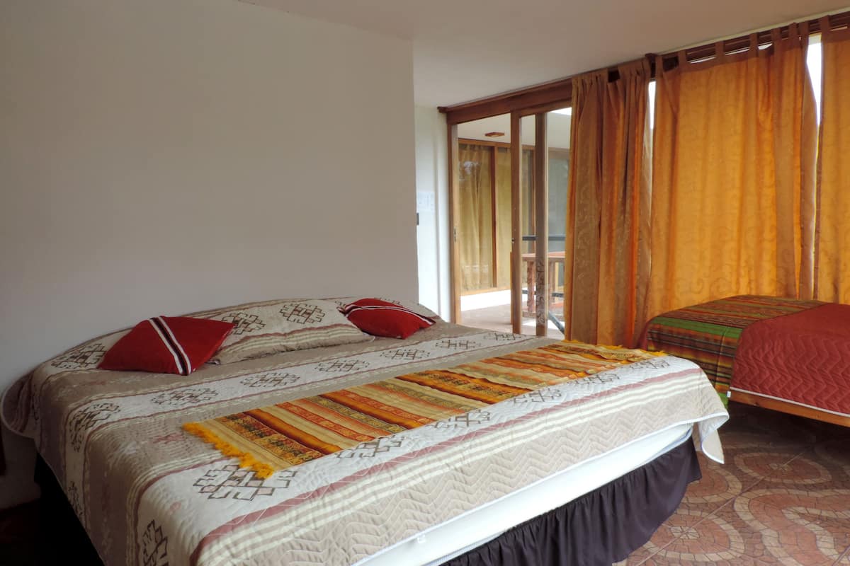 A bedroom with a large bed, a smaller bed, and a sliding glass door leading to an outdoor area.