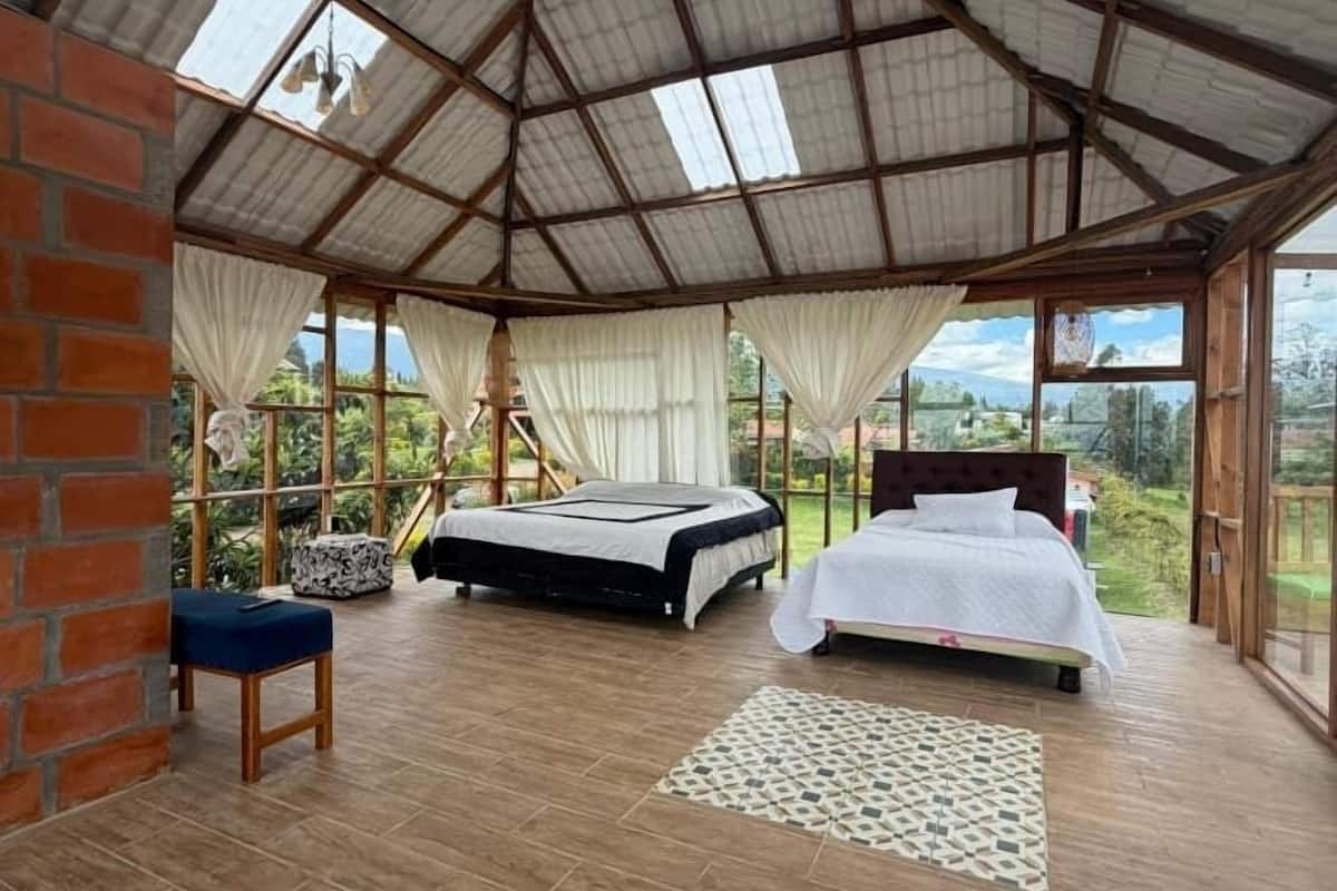 A spacious room with a large bed, a smaller bed, a sofa, and a view of the outdoors.