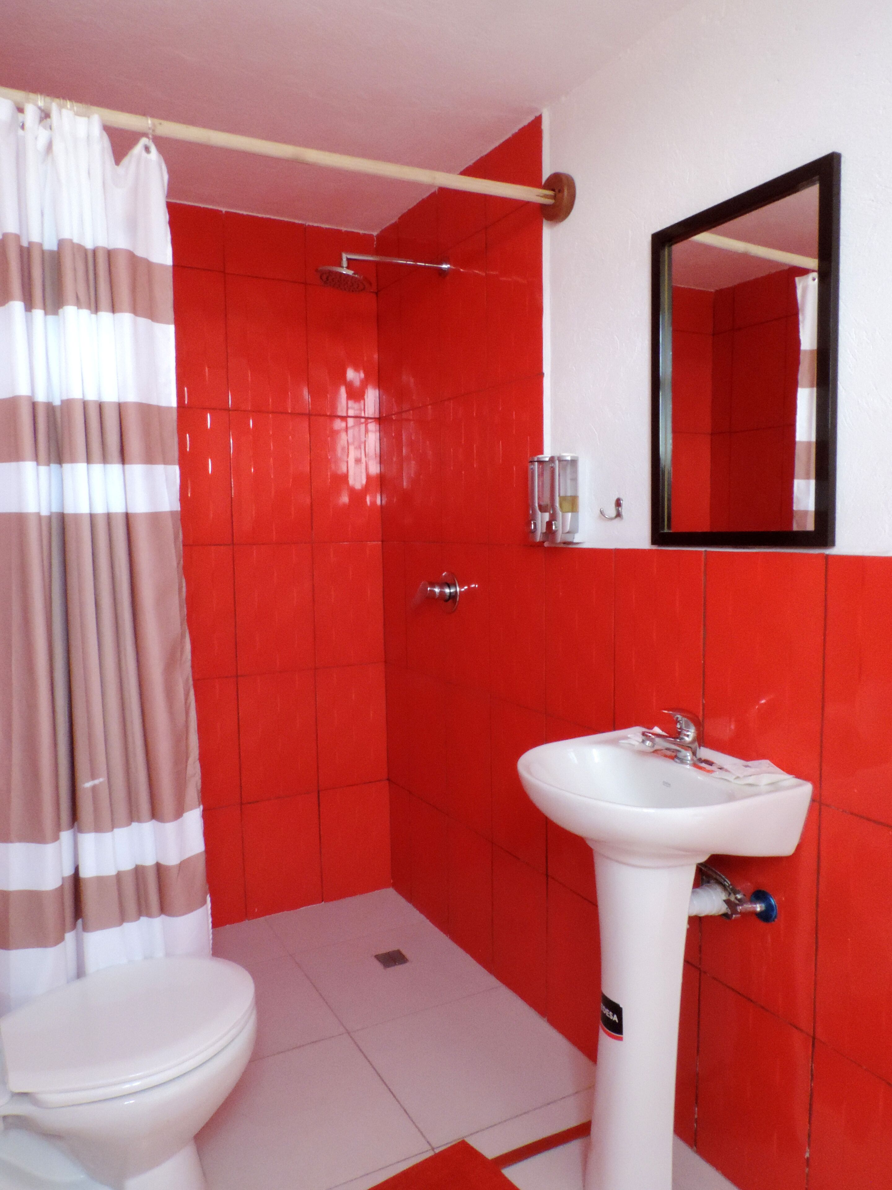 Baño con inodoro y lavamanos blancos, y zona de ducha.