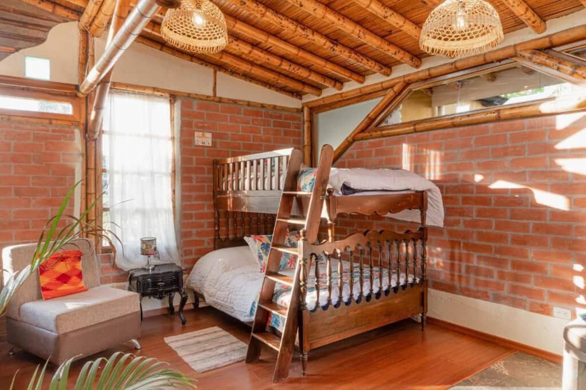 A rustic room with a wooden bunk bed, a small sofa, and a ladder leading to the upper bunk.