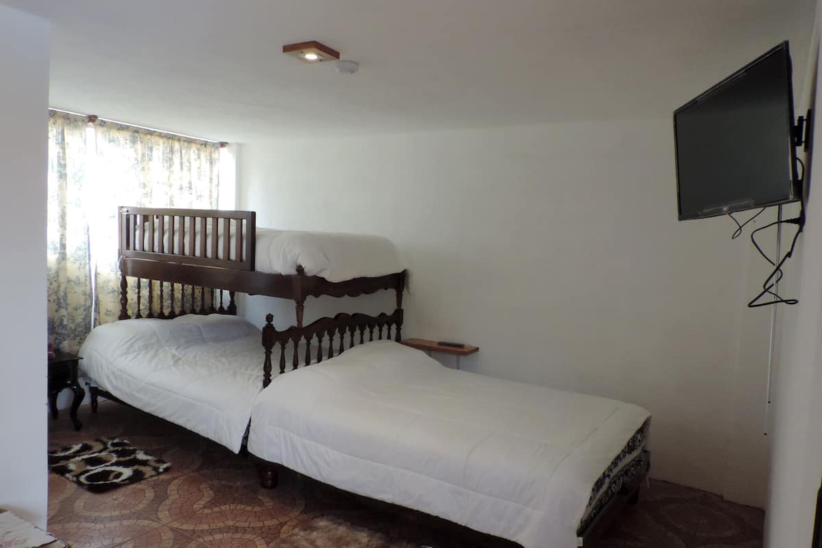 A single bed with a wooden headboard in a room with a tiled floor.