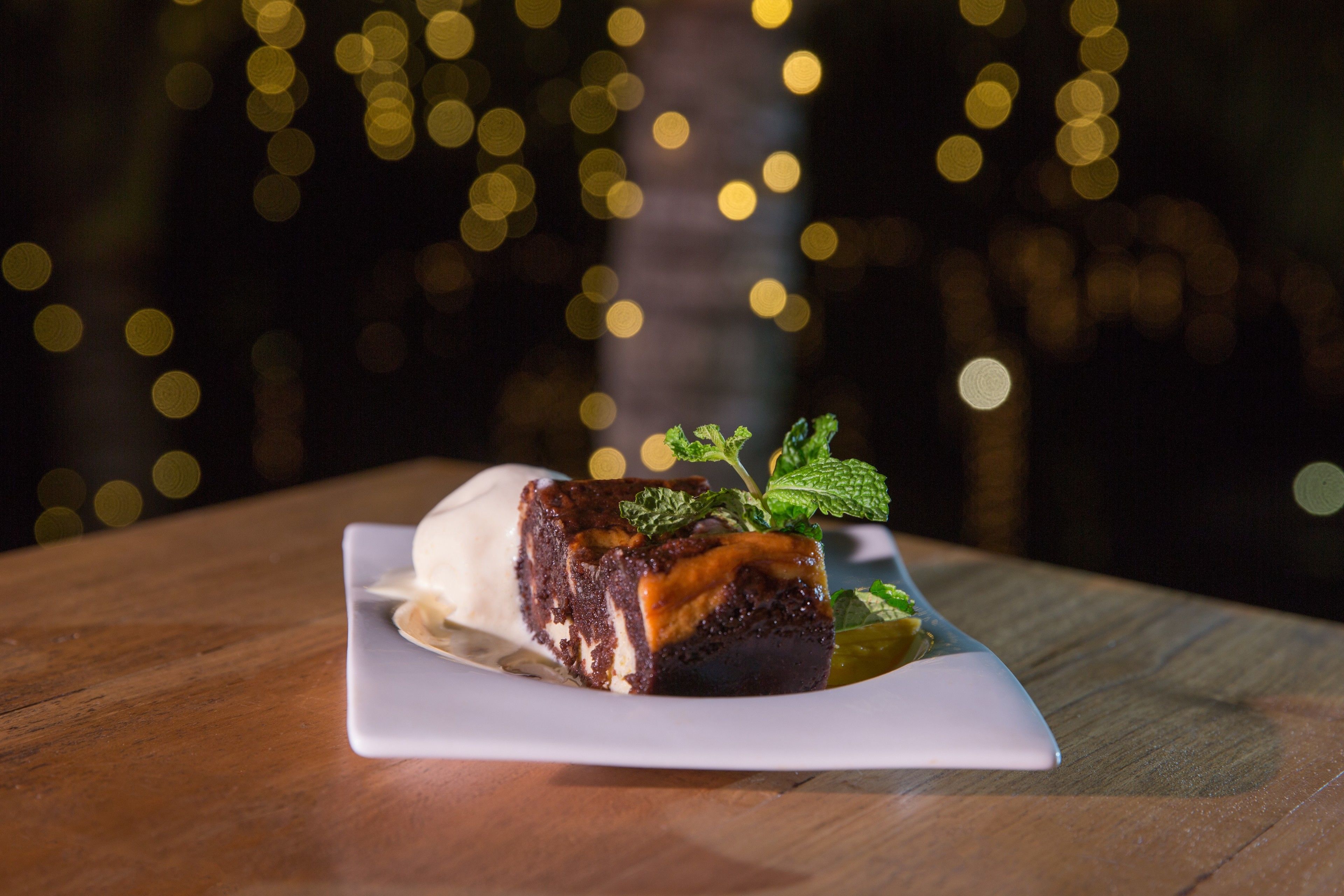 A dessert on a white plate with a blurred background of lights.