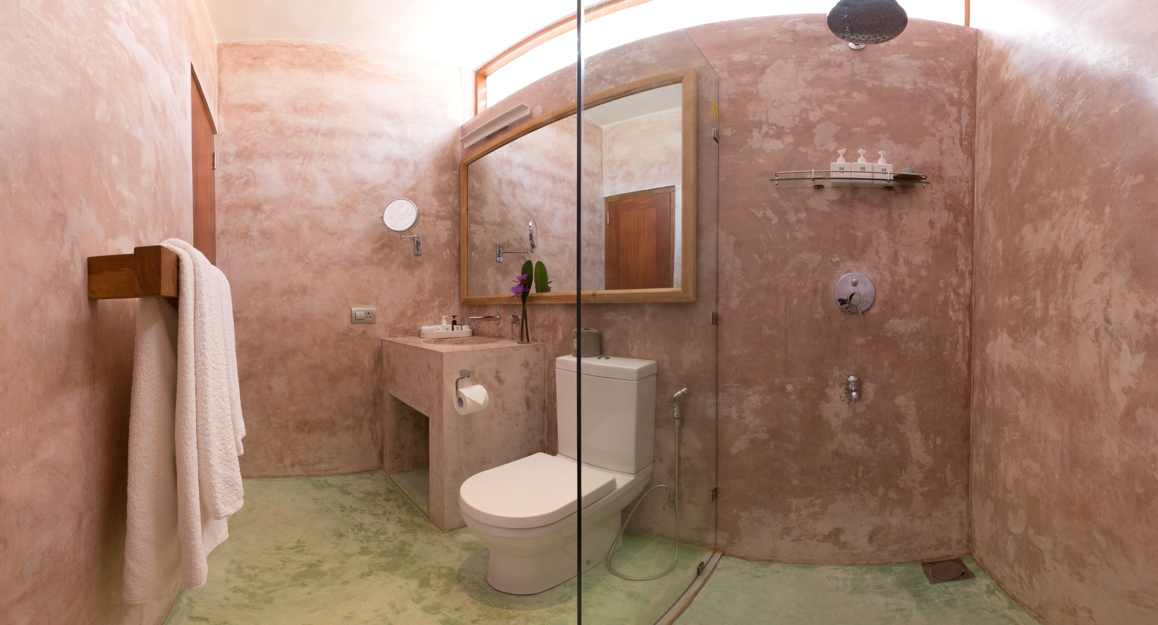 A bathroom with a toilet, sink, mirror, and shower.