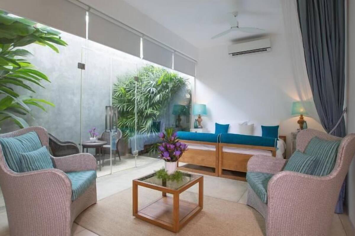 A modern living room with a glass partition, a sofa, a coffee table, and a ceiling fan.