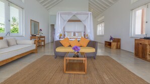 A spacious living room with a large bed, a sofa, a coffee table, and a TV stand. - Sri Sharavi Beach Villas & Spa (Thalaramba)