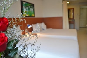 A hotel room with a bed, a nightstand, and a vase with flowers. - Nemo Hotel (Da Nang)
