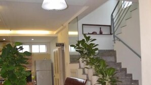 Un hall d’entrée avec un escalier, un espace détente et des plantes en pot.