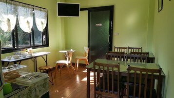 Un comedor con mesas y sillas, un televisor montado en la pared y un cartel que indica 'STAFF ONLY' en la puerta.