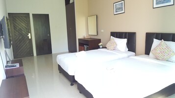 Een hotelkamer met twee bedden, een bureau, een spiegel en twee deuren.