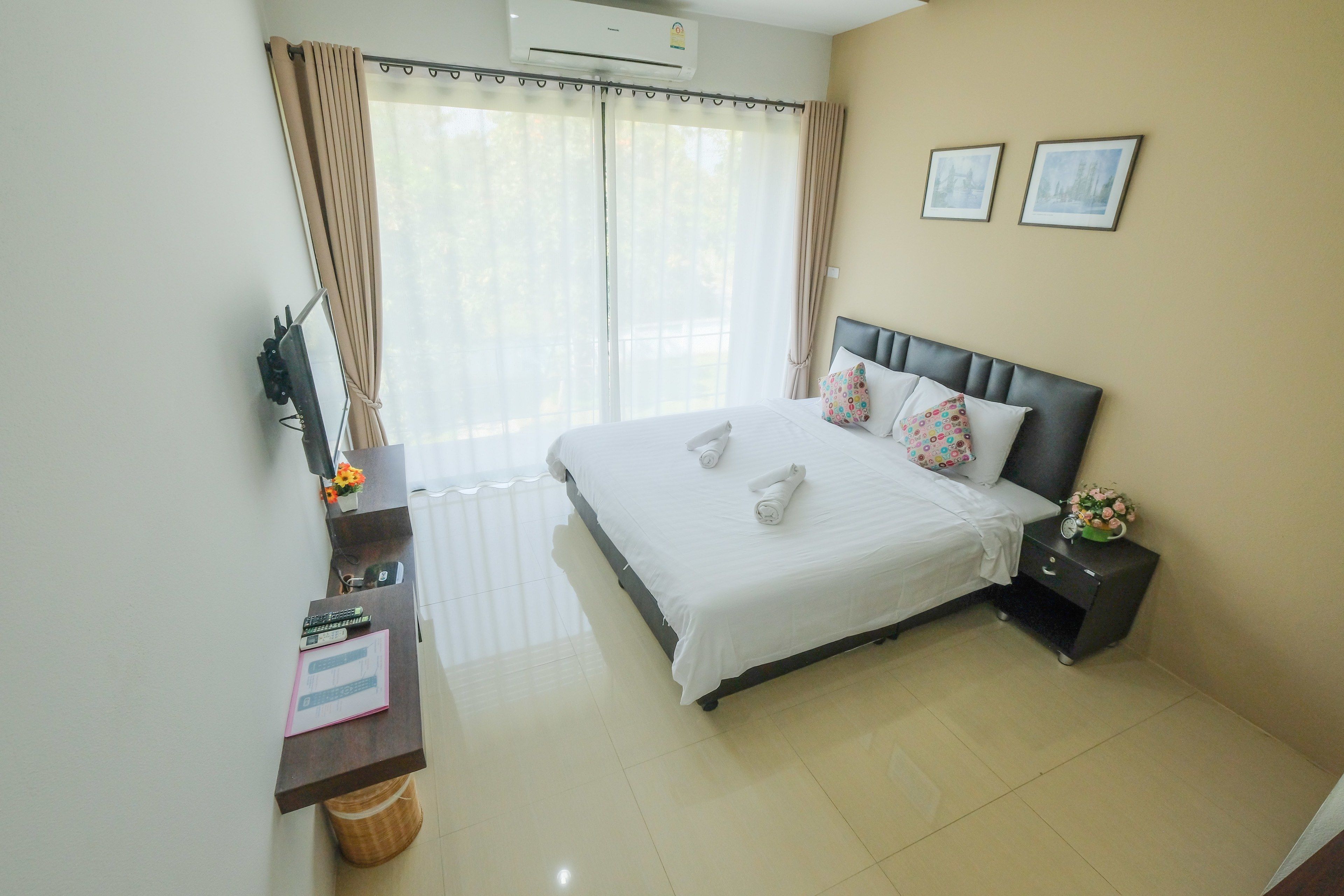 A hotel room with a bed, a desk, a chair, a nightstand, and a window with curtains.