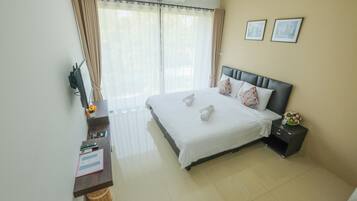 A hotel room with a bed, a desk, a chair, a nightstand, and a window with curtains.