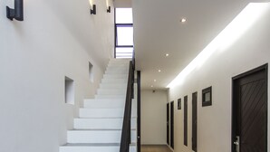 A modern staircase with a black handrail, white walls, and patterned floor tiles.