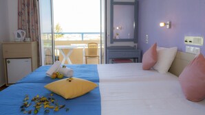 Habitación de hotel con cama, un pequeño escritorio con hervidor, una silla y vistas al exterior.