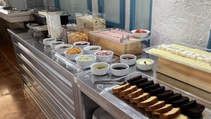 Un bufé con diferentes opciones de comida, incluyendo pan, gofres y queso.