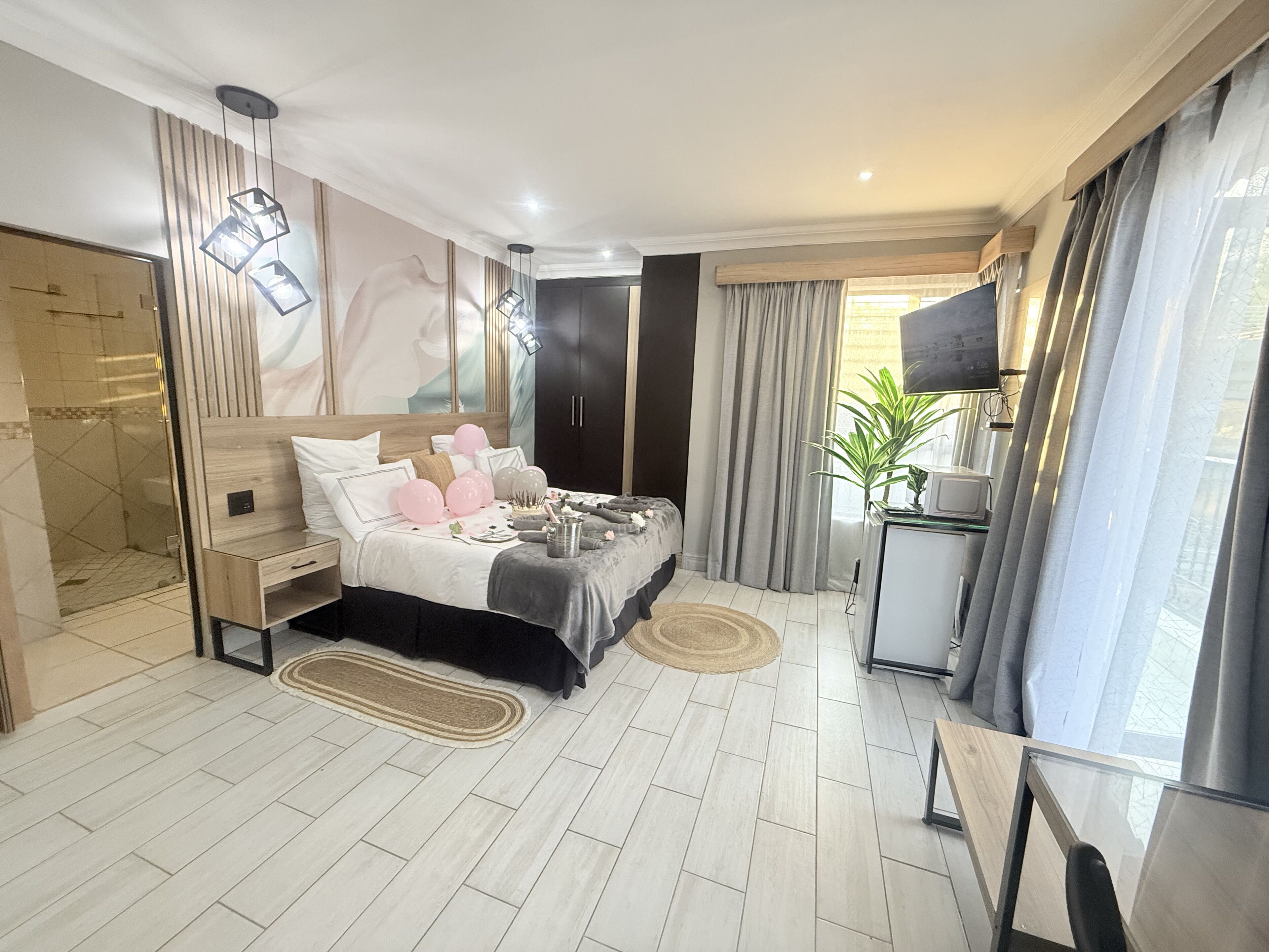 Un dormitorio moderno con cama, mesitas de noche, televisor y zona de ducha.