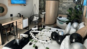 A modern bedroom with a bed, a desk, a chair, a TV, and a bathtub. - Africa Paradise Airport Boutique Hotel (Benoni)
