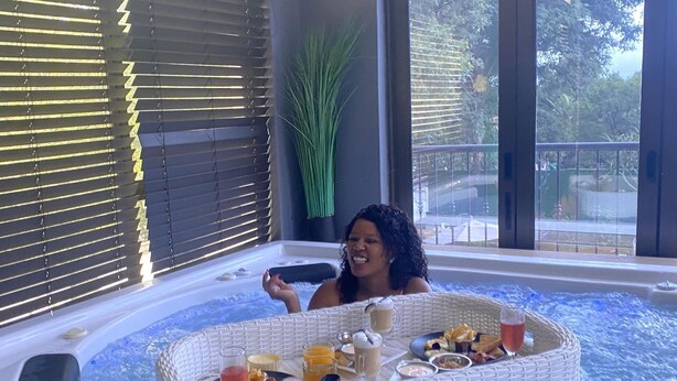 A hot tub with a wicker edge, filled with water and surrounded by a small table with various items. - Africa Paradise Airport Boutique Hotel (Benoni)