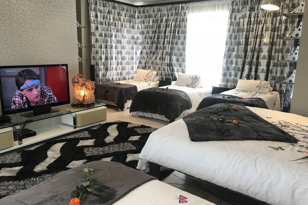 Een moderne hotelkamer met twee bedden, een televisie en een decoratief middelpunt.