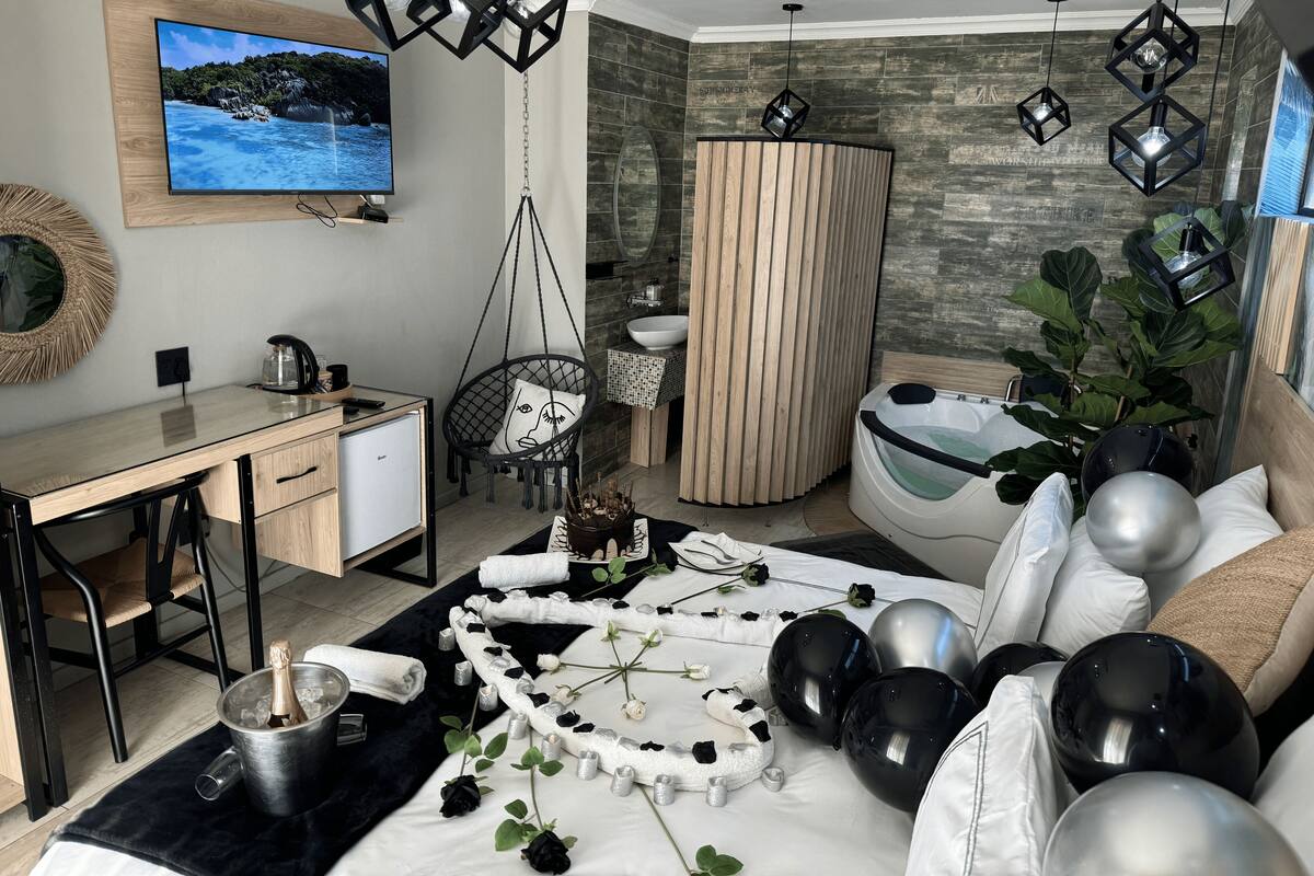 Een moderne slaapkamer met een bed, een bureau, een stoel, een televisie en een bad.