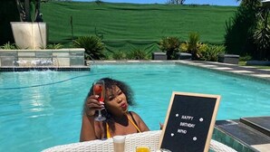 A person relaxing by a poolside table with a birthday greeting sign, surrounded by a lush green landscape. - Africa Paradise Airport Boutique Hotel (Benoni)