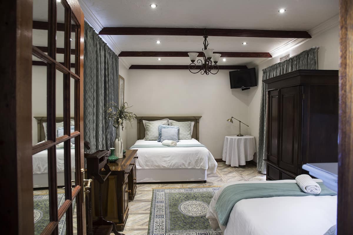Un dormitorio con una cama grande, un tocador, una mesita de noche, un espejo y una araña.