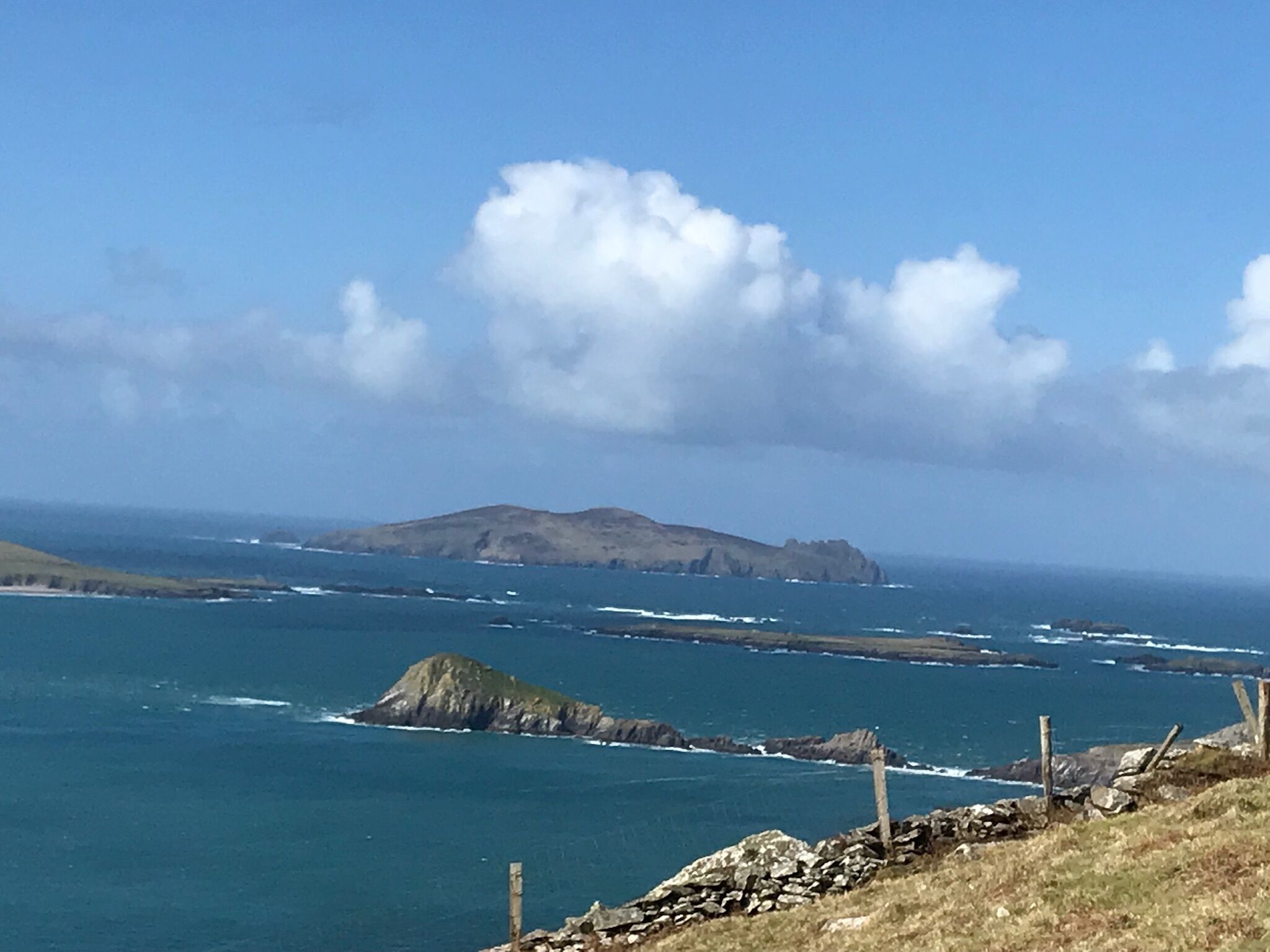 A coastal landscape with rocky outcrops and a clear sky.