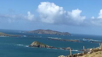 A coastal landscape with rocky outcrops and a clear sky.