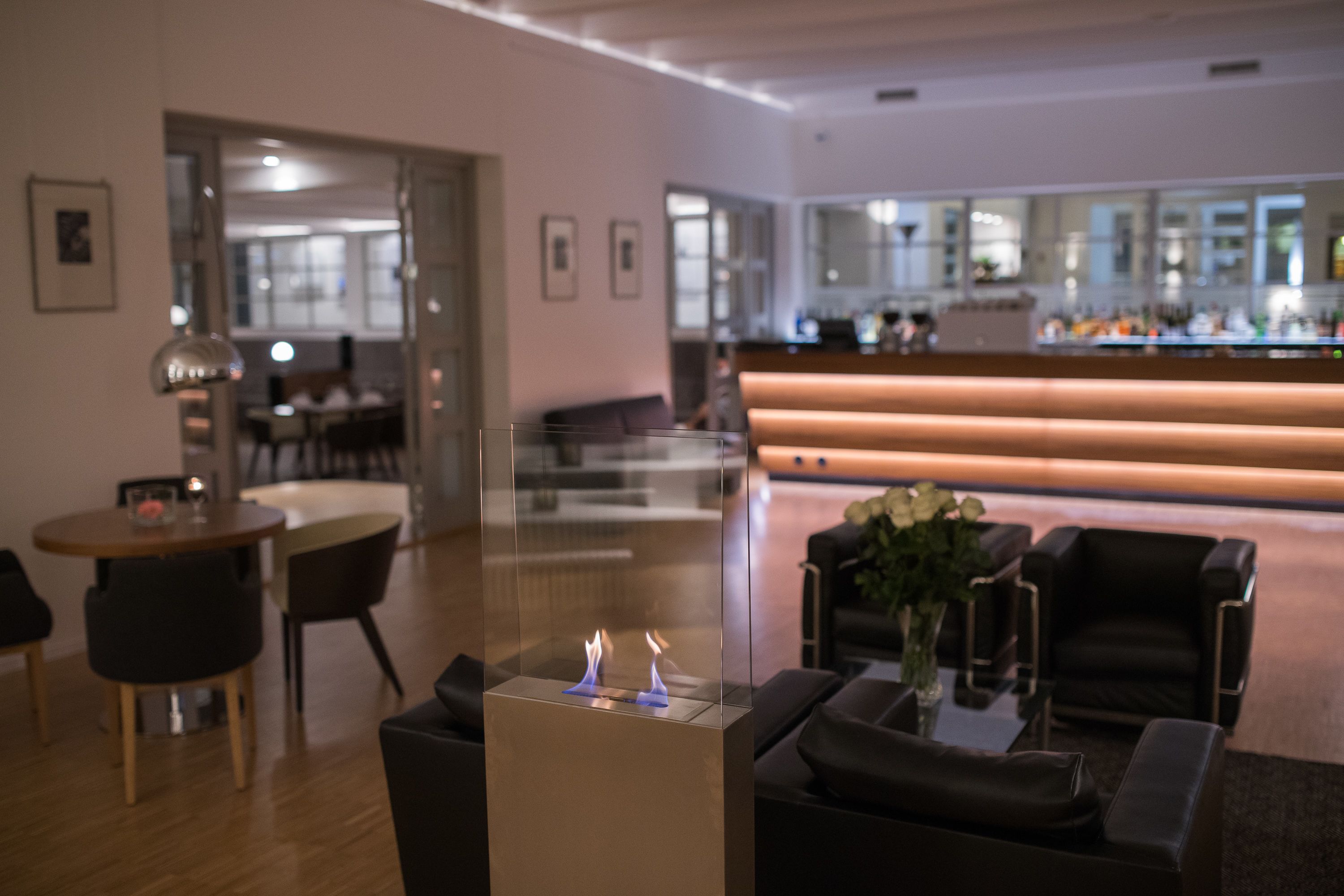A modern hotel lobby with a bar area, seating, and a fireplace.