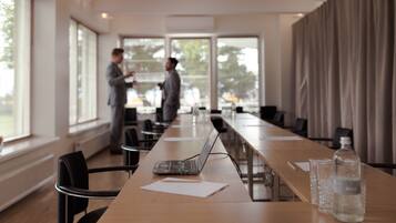 A conference room with a long table, chairs, a laptop, papers, and a water bottle.