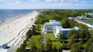 An aerial view of a coastal hotel with a beach, a parking lot, and a large building with multiple floors. - Rannahotell (Parnu)
