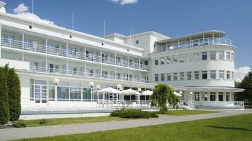 Un hotel de varios pisos con fachada blanca, múltiples balcones y zonas de estar al aire libre.