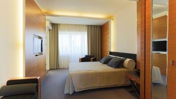 Una habitación de hotel moderna con una cama grande, un escritorio, una silla y un televisor.