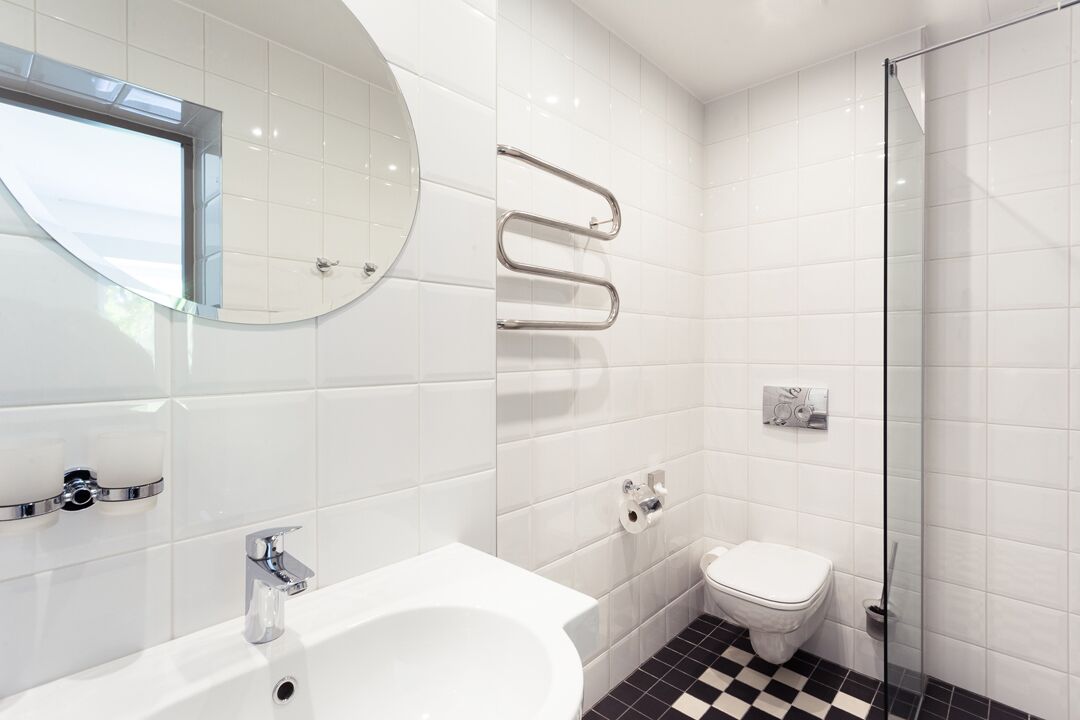 Un baño moderno con lavamanos blanco, inodoro y cabina de ducha con mampara de vidrio.